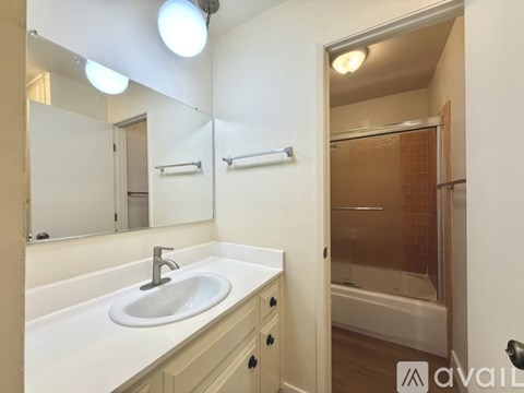 A bathroom with a sink, mirror, and a shower.