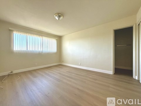 A room with wooden flooring and a window with blinds.