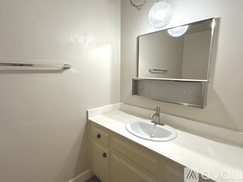 A white sink in a bathroom with a mirror above it.