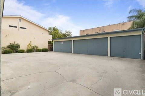 A large, empty parking lot with a building and a tree in the background.