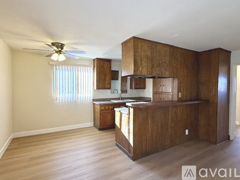 A kitchen area with wooden cabinets and a ceiling fan.