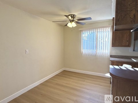 A room with a ceiling fan and wooden flooring.