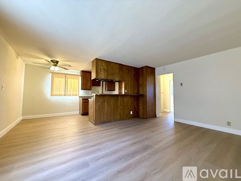 A spacious room with wooden floors and a kitchen area with a counter and cabinets.
