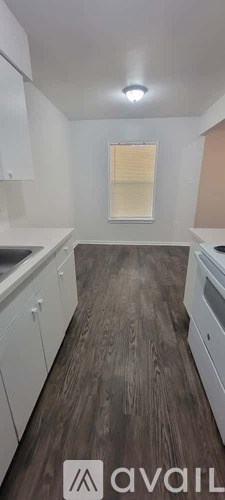 A kitchen with white cabinets and a wooden floor.