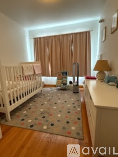 A baby's room with a crib, a changing table, and a rug with polka dots.