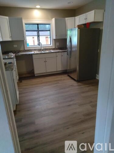 A kitchen with wooden floors and white cabinets.