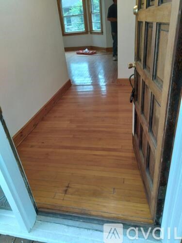 A wooden floor with a white door and a man in the background.
