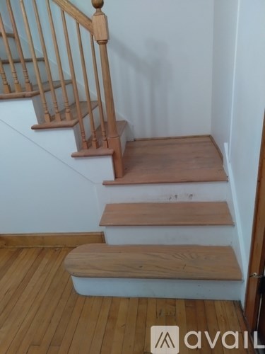 A wooden staircase with a white wall on one side and a wooden floor.