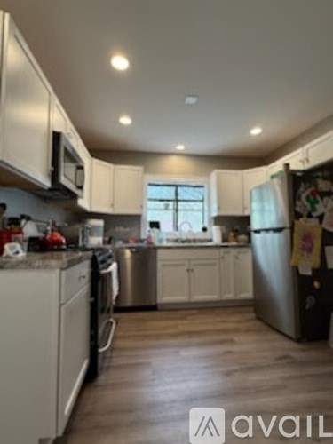 A kitchen with white cabinets and a wooden floor.