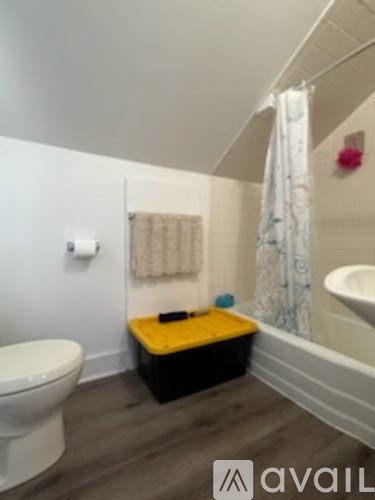 A bathroom with a white toilet, a yellow stool, and a white bathtub.