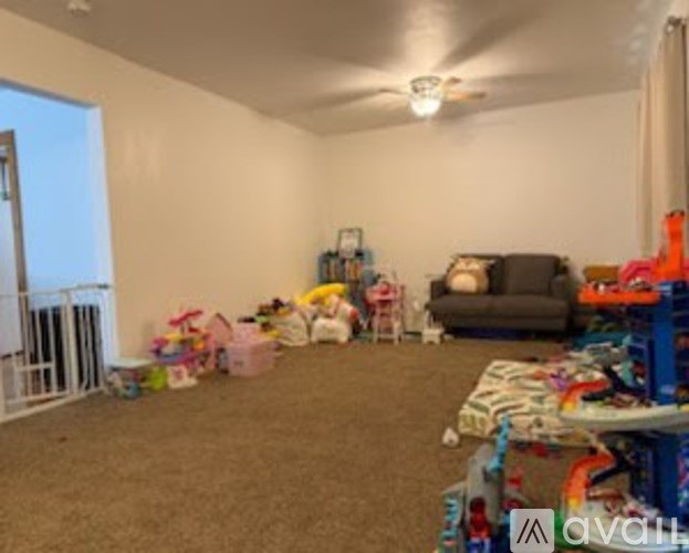 A room with a grey couch, a white chair, and a table with toys on it.