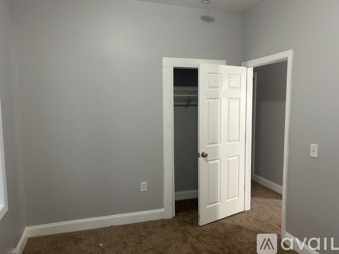 A room with a white door and carpeted floor.