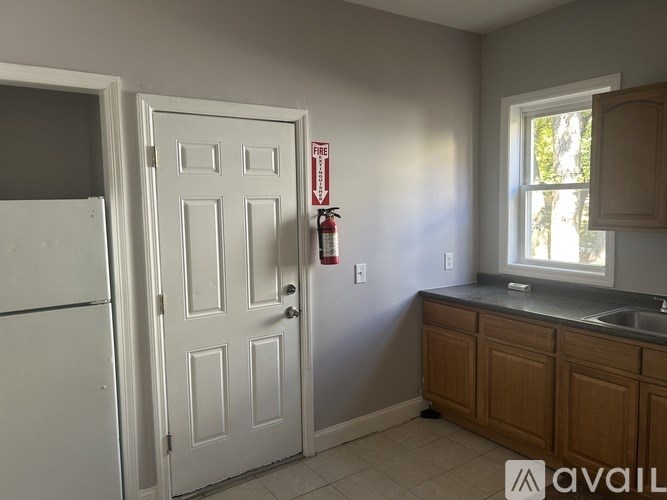 A kitchen with a white door, a white fridge, and a window.