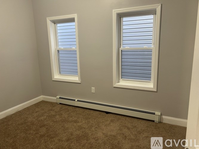 A room with two windows and a carpeted floor.