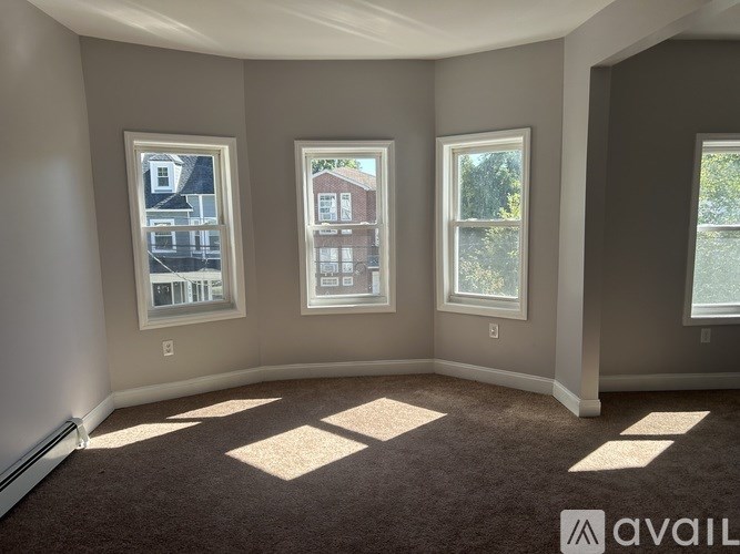 A room with three windows and a carpeted floor.