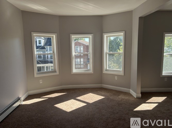 A room with three windows and carpeted floor.