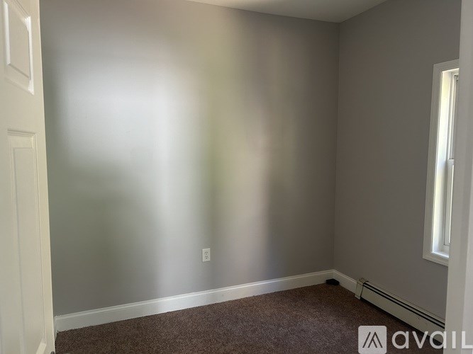 A room with a carpeted floor and a window on the right side.