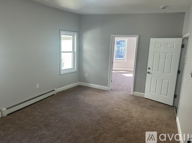 A room with carpeted floor, two windows, and a door.