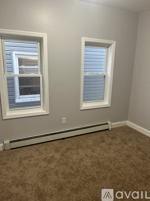 A room with two windows and carpeted floor.
