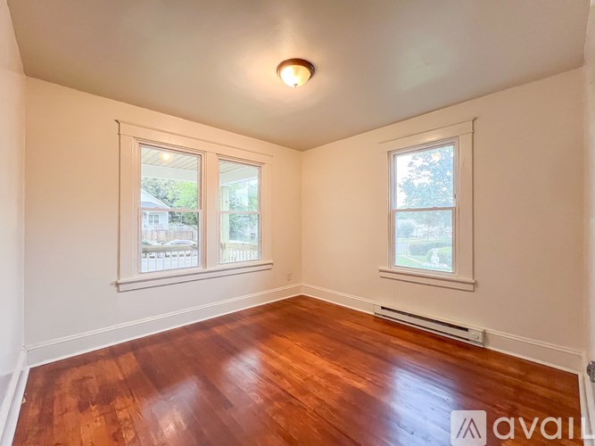 A room with wooden floors and two windows.
