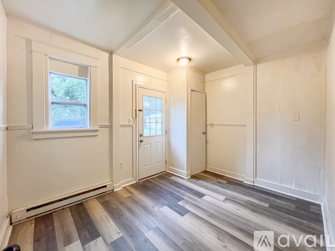 A room with wooden flooring and white walls.