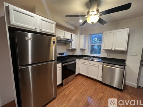 A kitchen with a stainless steel refrigerator and wooden floors.