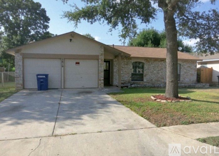 A house with a garage and a tree in front.