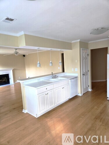 A kitchen with white cabinets and a wooden floor.