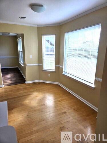A room with wooden floors and a window with blinds.