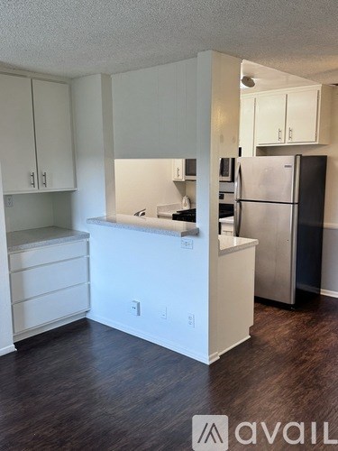 A kitchen with white cabinets and a black fridge.