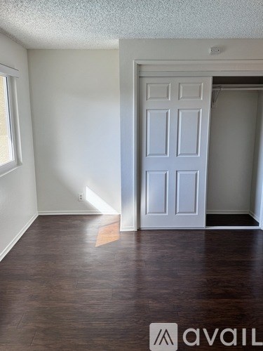 A room with a white door and wooden floor.