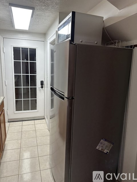 A kitchen with a refrigerator and a door with a window.