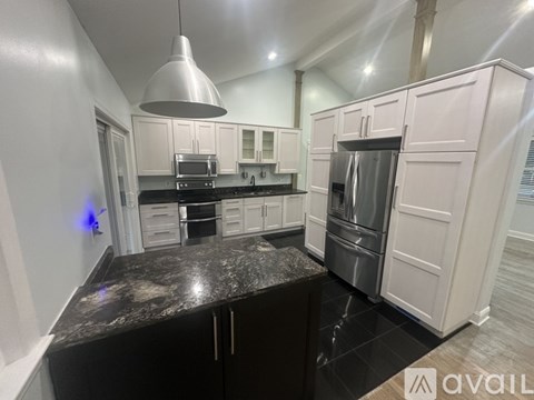 A kitchen with white cabinets and a black granite countertop.
