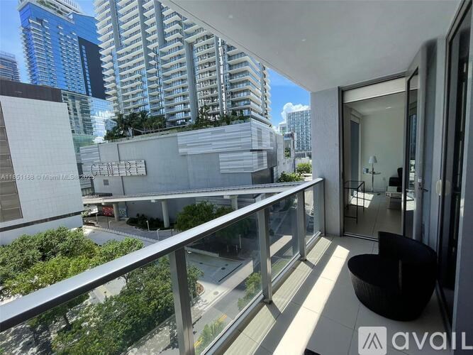 A balcony with a chair and a table overlooking a cityscape.