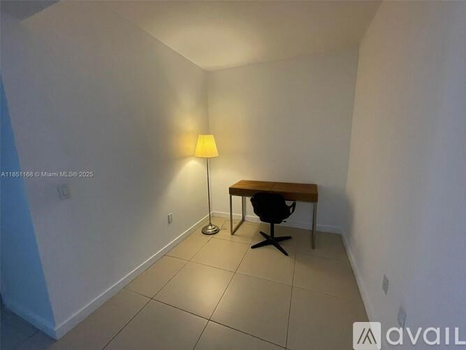 A lamp with a yellow shade is on a desk in a room.