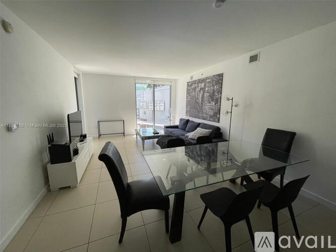 A modern dining room with a glass table and black chairs.
