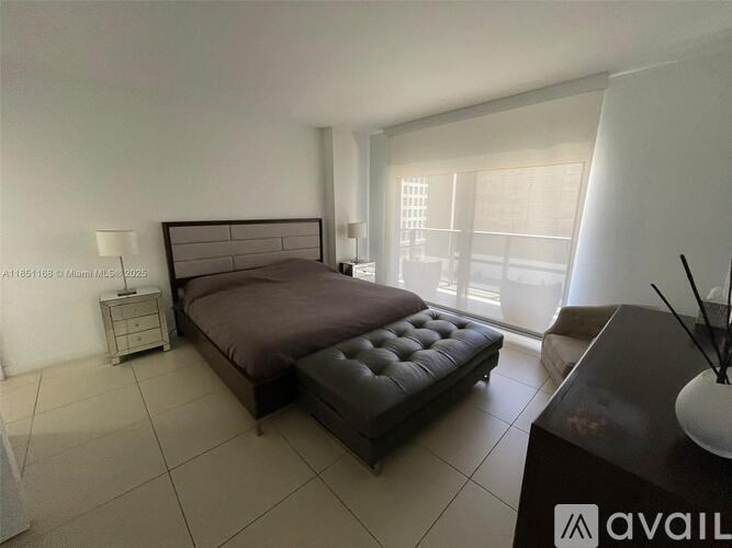 A bedroom with a large bed and a nightstand with a lamp.