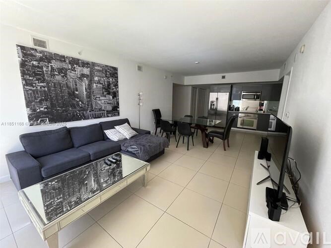 A living room with a blue couch and a black and white photo on the wall.
