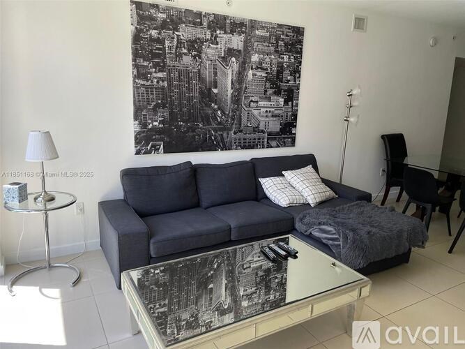 A living room with a blue couch and a black and white cityscape on the wall.