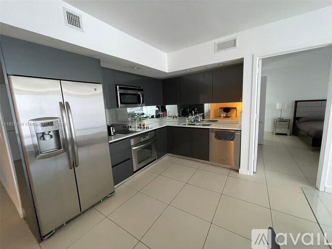 A modern kitchen with a refrigerator, microwave, and oven.