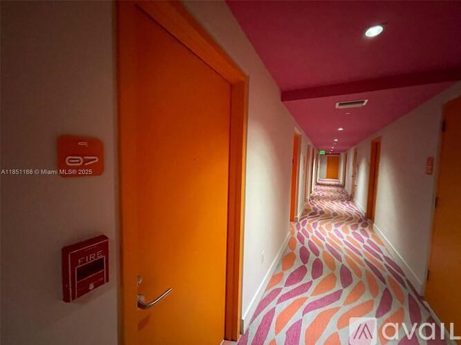 A hallway with a red fire extinguisher on the wall.