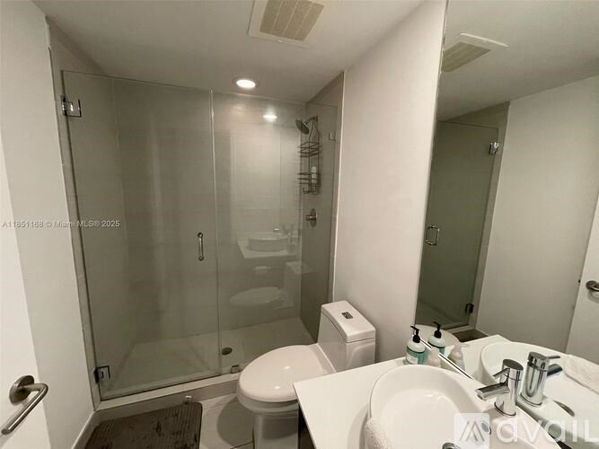 A white bathroom with a toilet, sink, and shower.