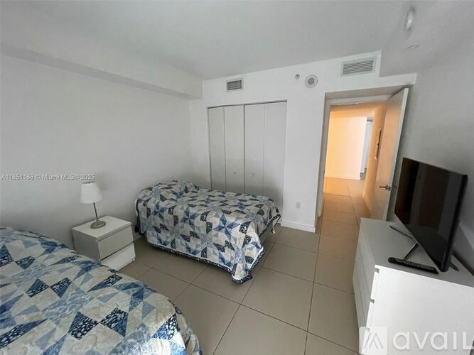 A bedroom with a bed, a dresser, and a television.