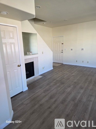 A spacious room with a fireplace and wood flooring.