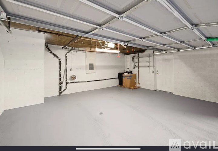 A large empty room with a white ceiling and walls, and a cardboard box on the floor.