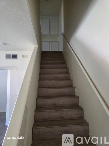 A staircase with a white wall on one side and a wooden floor.
