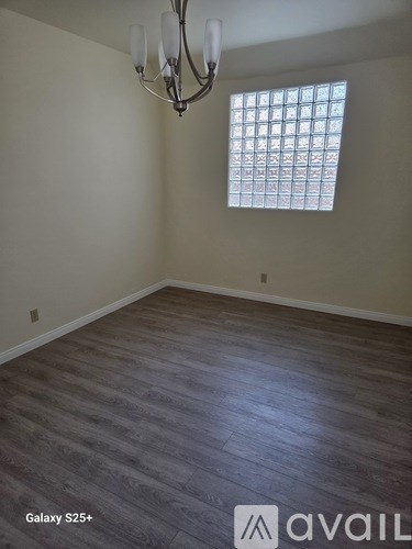 A room with a chandelier and a window with blinds.