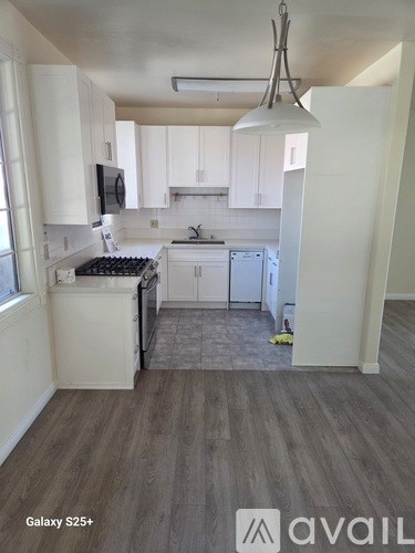A kitchen with white cabinets and a wood floor.