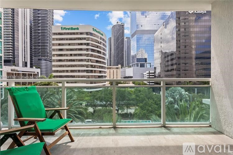 A balcony with a green chair and a view of a cityscape.