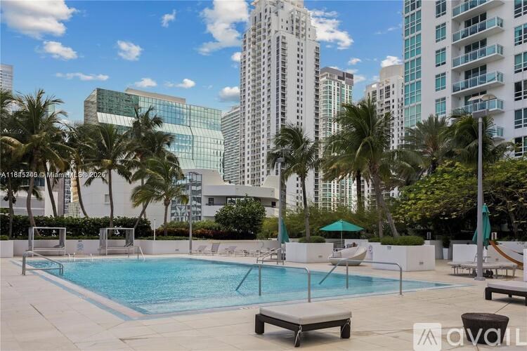 A pool surrounded by palm trees and modern buildings.